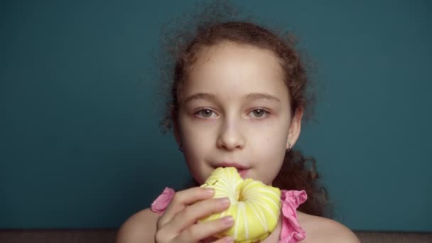 10岁的孩子在釉面上吃着甜甜的甜食甜甜圈 快乐的高加索小女孩吃着甜甜甜圈 一个吃甜糕点的孩子的嘴的特写 — 图库视频影像
