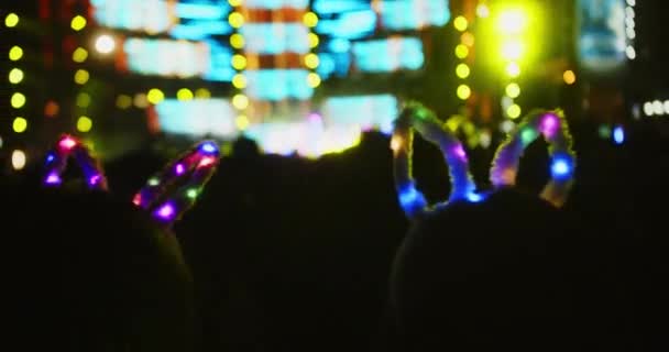 シルエットファンがステージ上の明るいカラフルなストローブライトで手を上げ ヘッドバンドの女の子が頭にライトを付け 人々はコンサートで楽しみを持っています — ストック動画