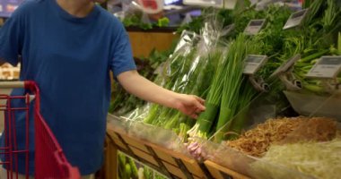 Çekici genç kadın yeşil soğan seçiyor, süpermarketten alışveriş yapıyor, sağlıklı yiyecekler alıyor, marketten yeşil soğan alıyor, süpermarketten. Market kavramı