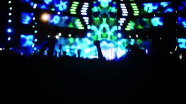 Siluet hayranları sahnede parlak flaş ışıkları önünde ellerini kaldırıyor, kafalarında ışık olan kızlar, konserde eğleniyorlar. Kalabalık dans ediyor.