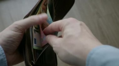 Erkek eli, içinde dolar ve avro olan bir cüzdanı açıyor. Finansal kriz, yoksulluk kavramı, ısınma için ödeme, ekonomik kriz ve iş yerindeki sorunlar, tasarruf eksikliği, küresel işsizlik