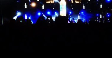 Siluet hayranları sahnede parlak flaş ışıkları önünde ellerini kaldırıyor, kafalarında ışık olan kızlar, konserde eğleniyorlar. Kalabalık dans ediyor.