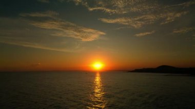 İnsansız hava aracından ateş etmek, deniz boyunca uçmak günbatımının arka planına ve bir balıkçı teknesine karşı. Denizde balıkçılar gün batımında balık tutuyorlar. Güzel, sakin bir gün batımı Denizde tek bir yat.