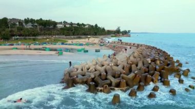 Mui Ne Vietnam 'daki sahil manzarasında, deniz dalgaları ve plajdaki bir drondan çekilen hava uçuşu. 4K.