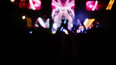 İnsanlar akşam konserinde ellerini çırpıp ışık gösterisiyle dans ediyorlar. Hayranlar sahnede parlak renkli flaş ışıklarıyla ellerini kaldırıyorlar. Kalabalık dans ediyor, performans rock grubu çekiyor, parti veriyor.