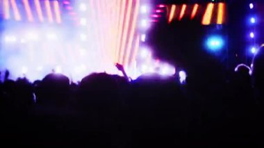 İnsanlar akşam konserinde ellerini çırpıp ışık gösterisiyle dans ediyorlar. Hayranlar sahnede parlak renkli flaş ışıklarıyla ellerini kaldırıyorlar. Kalabalık dans ediyor, performans rock grubu çekiyor, parti veriyor.