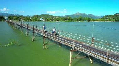 Ormandan yola doğru tahta bir köprüde motorsikletle giden hava manzaralı motorcular. Motosikletliler yeşil ahşap yolda onun motosikletini sürüyorlar. Yolculuk sırasında bisiklet süren bir adam. Özgürlük ve macera