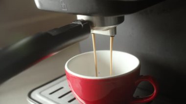 Kahve makinesinden fincana kahve dökülüyor. Ev yapımı sıcak Espresso. Filtre tutacağı kullanılıyor. Taze kahve akıyor. Sabahları kavrulmuş sade kahve içmek..