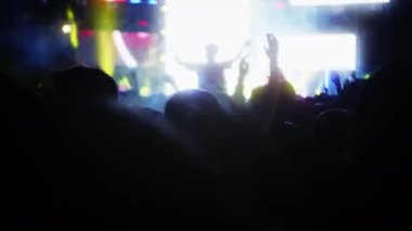İnsanlar akşam konserinde ellerini çırpıp ışık gösterisiyle dans ediyorlar. Hayranlar sahnede parlak renkli flaş ışıklarıyla ellerini kaldırıyorlar. Kalabalık dans ediyor, performans rock grubu çekiyor, parti veriyor.