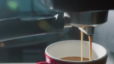Kahve makinesinden fincana kahve dökülüyor. Ev yapımı sıcak Espresso. Filtre tutacağı kullanılıyor. Taze kahve akıyor. Sabahları kavrulmuş sade kahve içmek..