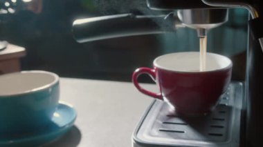 Kahve makinesinden fincana kahve dökülüyor. Ev yapımı sıcak Espresso. Filtre tutacağı kullanılıyor. Taze kahve akıyor. Sabahları kavrulmuş sade kahve içmek..
