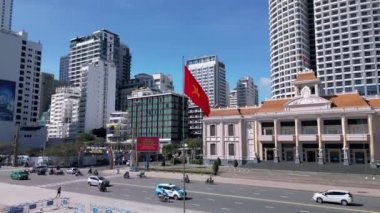 Nha Trang Su Kukla Tiyatrosu ve Vietnam Bayrağı. Nha Trang, Vietnam - 16 Şubat 2023 Nha Trang Şehir Merkezi Vietnam bayrağı bir direğe asılı ve rüzgarda savruluyor. 4K.