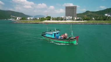Balıkçılar kayık hangarından çıkıyorlar. Güneşli bir sabah, bir balıkçı teknesi bir deniz ürünü yakalamak için aceleyle denize açılır. Asya balıkçı tekneleri. Vietnam 'daki balıkçı kasabası Nha Trang..