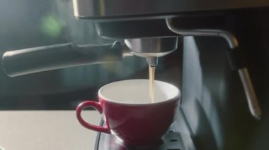 Kahve makinesinden fincana kahve dökülüyor. Ev yapımı sıcak Espresso. Filtre tutacağı kullanılıyor. Taze kahve akıyor. Sabahları kavrulmuş sade kahve içmek..
