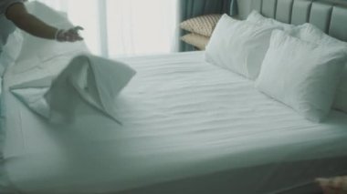 Kadınlar odadaki yatağı değiştiriyor. Çalışanlar, otelin iki hizmetçisi, müşteri odasındaki yatağı profesyonel olarak hazırlıyorlar. Beş yıldızlı otel konsepti ve kaliteli oda servisi. 4K.
