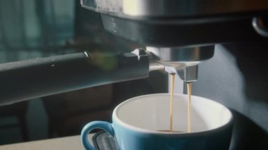 Kahve makinesinden fincana kahve dökülüyor. Ev yapımı sıcak Espresso. Filtre tutacağı kullanılıyor. Taze kahve akıyor. Sabahları kavrulmuş sade kahve içmek..