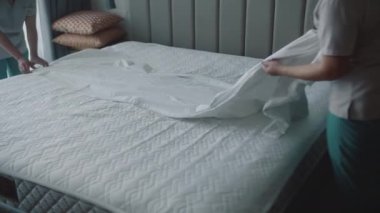 Kadınlar odadaki yatağı değiştiriyor. Çalışanlar, otelin iki hizmetçisi, müşteri odasındaki yatağı profesyonel olarak hazırlıyorlar. Beş yıldızlı otel konsepti ve kaliteli oda servisi. 4K.