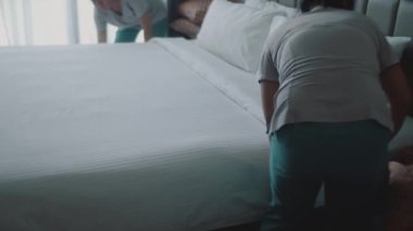 Kadınlar odadaki yatağı değiştiriyor. Çalışanlar, otelin iki hizmetçisi, müşteri odasındaki yatağı profesyonel olarak hazırlıyorlar. Beş yıldızlı otel konsepti ve kaliteli oda servisi. 4K.
