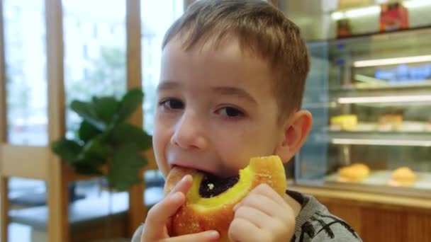 Glückliches Kind Isst Einem Café Ein Brötchen Mit Marmelade Und — Stockvideo