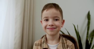 Portre Komik küçük kız kameraya bakıyor evde kanepede oturuyor, güzel yüzlü şirin çocuk kanepede oturuyor. Mutlu bir çocukluk kavramı.
