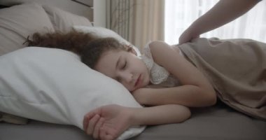 Küçük çocuk beşiğinde tatlı tatlı uyuyor ve uykusunda gülümsüyor. Anne kızına bakıyor. Yan yatmış uyuyan çocuk bebekle yüzleş. İzleme, gece yarısı uyuyan bebeği vurdu. Yatakta uyuyan bebek