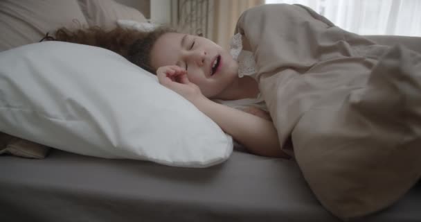 一个穿着蓝色睡衣的可爱有趣而快乐的小女孩的画像早上在床上醒来 小孩笑着看着他的父母 笑着伸出手来 又藏在毛毯下 — 图库视频影像