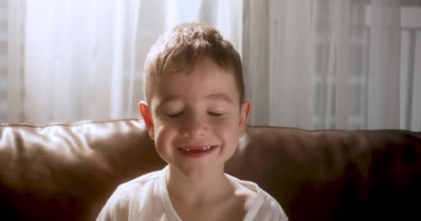 Портрет Смешной Маленький Мальчик Улыбающийся Ребенок Смотрит Камеру Сидят Диване — стоковое видео