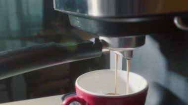 Kahve makinesinden fincana kahve dökülüyor. Ev yapımı sıcak Espresso. Filtre tutacağı kullanılıyor. Taze kahve akıyor. Sabahları kavrulmuş sade kahve içmek..