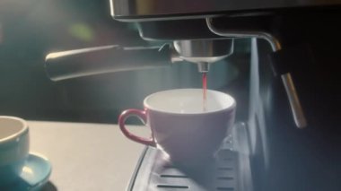 Kahve makinesinden fincana kahve dökülüyor. Ev yapımı sıcak Espresso. Filtre tutacağı kullanılıyor. Taze kahve akıyor. Sabahları kavrulmuş sade kahve içmek..