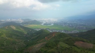 Nha Trang 'ın havadan görünüşü ve şehrin etrafındaki ağaçlık dağlar, Vietnam. Kıyı şehrinde uçan insansız hava aracı ve inanılmaz yeşil tepeler. Vietnamlılar. Nui Co Tien dağının manzarası. 4K.