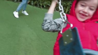 Mutlu gülen çocuklar parkta salıncakta salıncakta bir kızla küçük bir oğlan, güneşli bir günde salıncakta sallanıyor, neşeli çocuklar uçuyor, çocuklar gülüyor ve gülümsüyor,