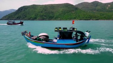 Balıkçılar kayık hangarından çıkıyorlar. Güneşli bir sabah, bir balıkçı teknesi bir deniz ürünü yakalamak için aceleyle denize açılır. Asya balıkçı tekneleri. Vietnam 'daki balıkçı kasabası Nha Trang..
