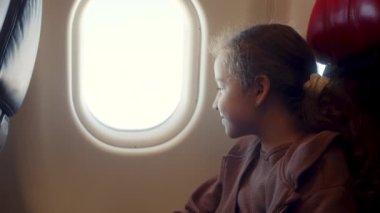 Çocuk uçak penceresinde oturuyor ve uçakta uçarken küçük kağıt uçakla oynuyor. Childs 'ın eli uçak penceresinin arka planında küçük kağıt uçakla.
