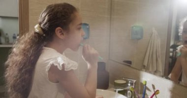 Portre, banyoda dişlerini fırçalayan ve gülümseyen mutlu bir çocuk. Bebek günlük sağlık hizmeti rutini. Kafkasyalı çocuk evde aynaya bakıyor. Yaşam biçimi.