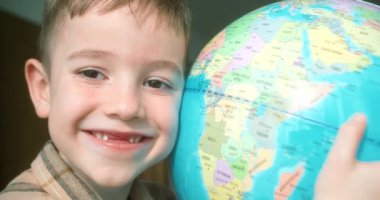 Küçük liseli kız portresi, güneşli bir odada durmuş, dünya ile kucaklaşıyor. Sevimli Çocuk gülümseyen kameraya bakıyor. Yanında küre tutuyor. Okul çocuğu için teknoloji, dünyaya bakan çocuk için teknoloji.