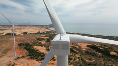 Geniş rüzgar türbinleri. Saha manzaralı, parlak turuncu günbatımı. Mavi gökyüzü parkı yavaş çekim drone dönüşü. Siluetler yel değirmenleri, büyük turuncu güneş diski yaz merceği parlamaları. Alternatif enerji.