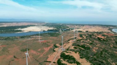 Geniş rüzgar türbinleri. Saha manzaralı, parlak turuncu günbatımı. Mavi gökyüzü parkı yavaş çekim drone dönüşü. Siluetler yel değirmenleri, büyük turuncu güneş diski yaz merceği parlamaları. Alternatif enerji