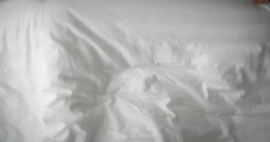 Mutlu, neşeli, beyaz pijamalı bir çocuğun portresi. Sabah yatağında uyanır, ailesine gülümserken bakar. Kahkahalar atar ve tekrar battaniyenin altına saklanır.