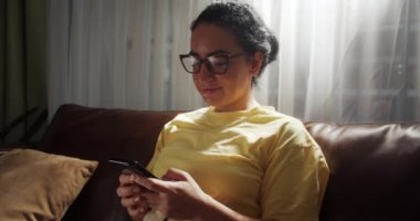 Çekici Hintli kadın evde tek başına duruyor ve dokunmatik ekranda akıllı bir telefon numarası tutuyor. Appon cep telefonu, web sörfü web sitesi kullanan neşeli genç bayan, ürünleri on-lin 'de almayı seçin