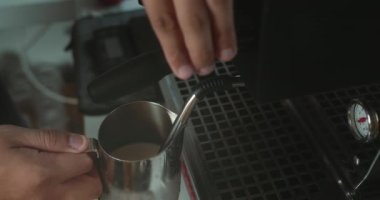 Cappuccino için sütlü kahve, kahve buharı sütü hazırlıyorum. Kahveci latte hazırlıyor. Kahve latte. Kahveci kahve makinesinden çıkan sıcak buharla sürahiye süt döker. Süt köpüğü yapma süreci.