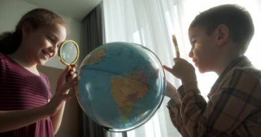 Çocuklar evde otururken gün batımını seyrediyor. Sabahları gün batımında çocuklar, Dünya 'lı şirin çocuklar ve büyüteç, okul çocuğu için teknoloji, dünya' ya bakıyor.