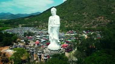 Vietnam 'daki dev Buda heykelinin etrafında uçan hava manzarası, yeşil bitki ve ağaçların arka planına karşı. Beyaz Büyük Buda ilgi alanlarından biri.