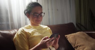 Çekici Hintli kadın evde tek başına duruyor ve dokunmatik ekranda akıllı bir telefon numarası tutuyor. Appon cep telefonu, web sörfü web sitesi kullanan neşeli genç bayan, ürünleri on-lin 'de almayı seçin