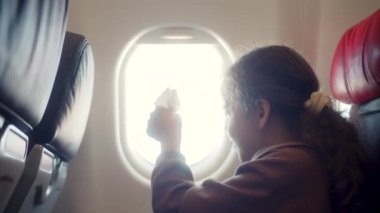 Çocuk uçak penceresinde oturuyor ve uçakta uçarken küçük kağıt uçakla oynuyor. Childs 'ın eli uçak penceresinin arka planında küçük kağıt uçakla.