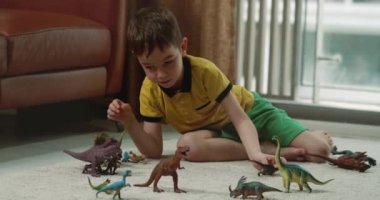 Dinozorculuk oynayan sevimli çocuk komik küçük çocuk. Küçük çocuk evde eğlenen paleontolojiyi anlatıyor. Küçük kardeş çocuklar oturma odasında oyuncak oyunu oynuyorlar. 4K.
