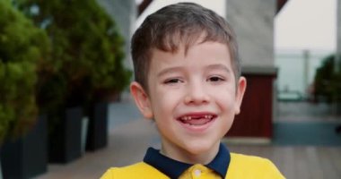 Yaz gününde şehirde sokakta dikilen mutlu çocuk. Parkta erkek yüzü var. Komik bir portre Çocuk. Gülen surat. Çocuk kameraya gülümser. Çocuk rüyası. Portre yakın plan. Sokaktaki mutlu çocuk.