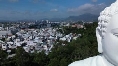 Vietnam 'ın Büyük Buddha' sı üzerindeki hava manzarası. Sinek kamerası, yüksek pagoda ve uçsuz bucaksız mavi gökyüzüne karşı büyük beyaz Buda heykeline iniyor. Beyaz Buda Vietnam 'ı Nha Trang Vietnam' ın simgelerinden biridir. 4K