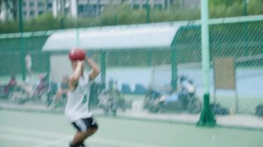 Tanınmayan bir oyuncunun basketbol potasına top attığını görünce, top ringe çarpıyor ve sayı yapıyor. Gerçek zamanlı çekim..