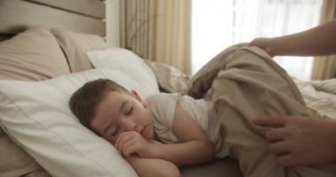 Küçük çocuk beşiğinde tatlı tatlı uyuyor ve uykusunda gülümsüyor. Anne kızına bakıyor. Yan yatmış uyuyan çocuk bebekle yüzleş. İzleme, gece yarısı uyuyan bebeği vurdu. Yatakta uyuyan bebek