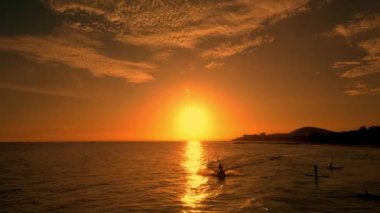 Sörfçüler büyük dalgalarla arka planda güzel bir günbatımına karşı Vietnam denizinde sörf yapar. Sporcular, mutlu insanlar, sörf tahtasında deniz dalgası sürmekten mutlular. İnsansız hava aracından inerek gün batımında deniz arka planında sörf yapıyorlar.